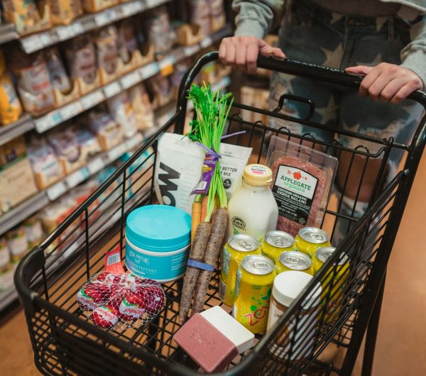 A grocery cart with fresh and packaged food items, representing grocery shopping on a budget.